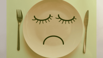 Trauriger Gesichtsausdruck auf einem Teller - Symbol für den Hungerstoffwechsel in Bezug auf Ernährung und Gewichtsverlust.