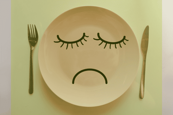 Trauriger Gesichtsausdruck auf einem Teller - Symbol für den Hungerstoffwechsel in Bezug auf Ernährung und Gewichtsverlust.